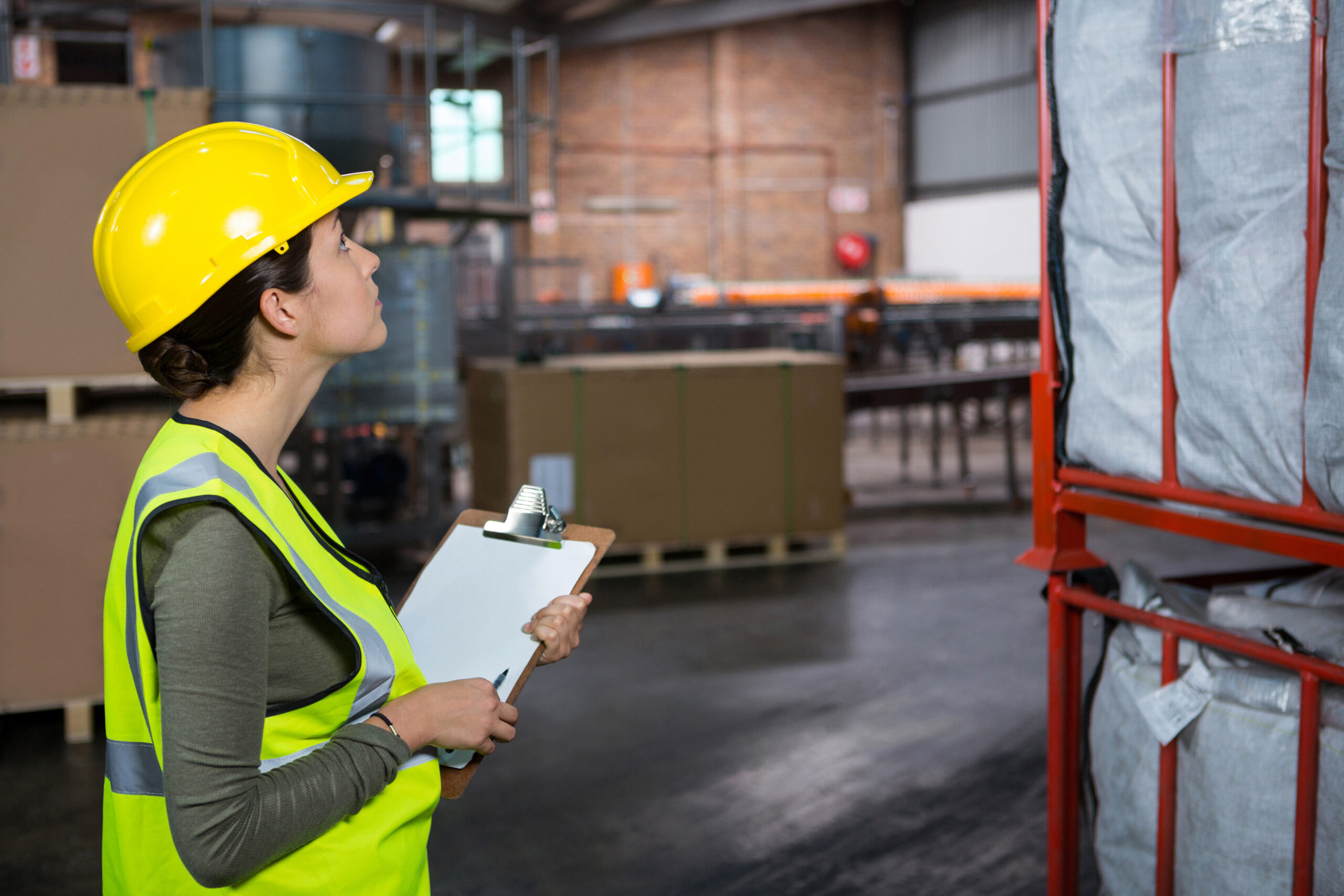 Side view of confident female worker examining products in warehouse